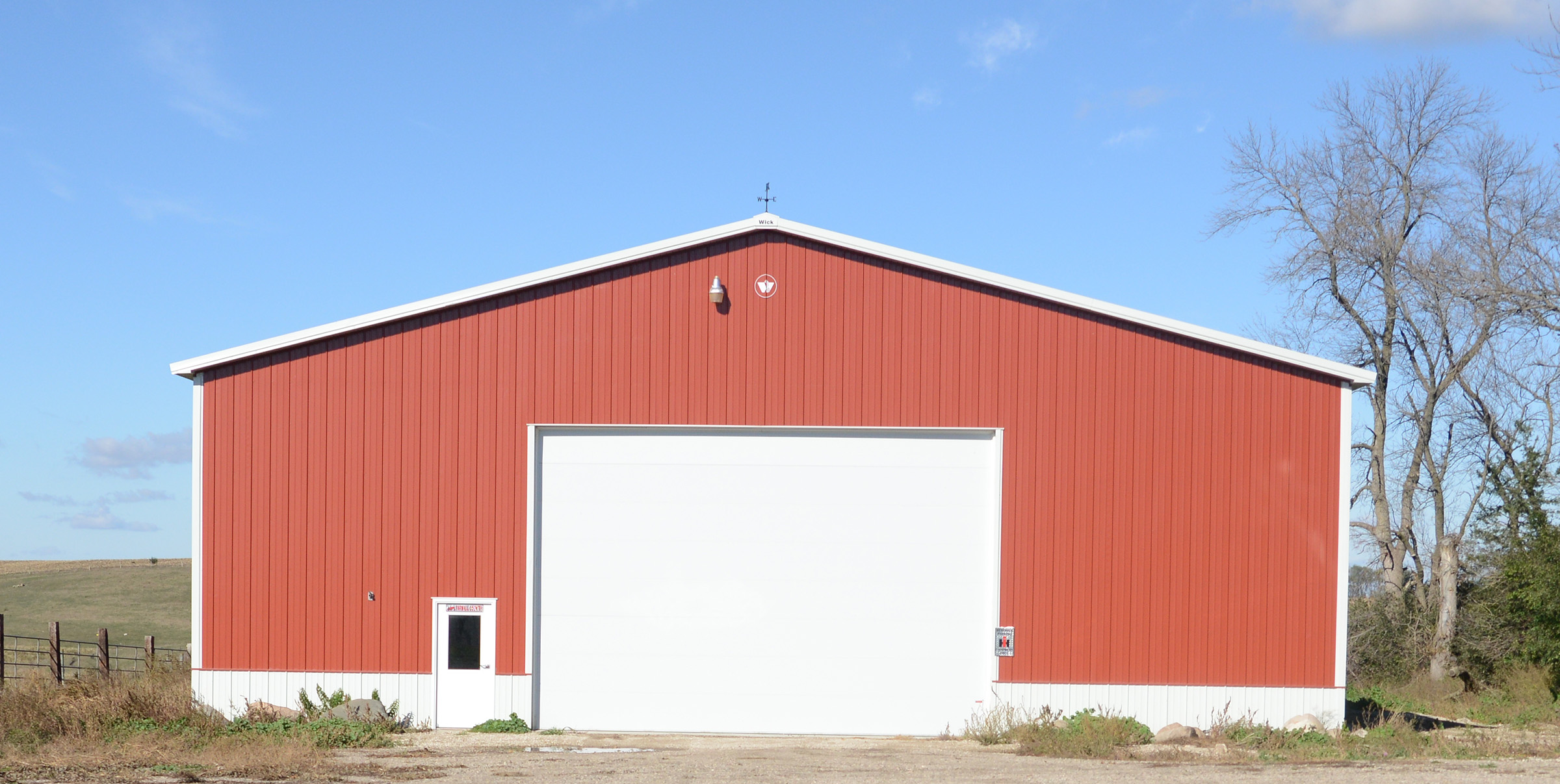 Red post frame suburban building with white trim and garage door