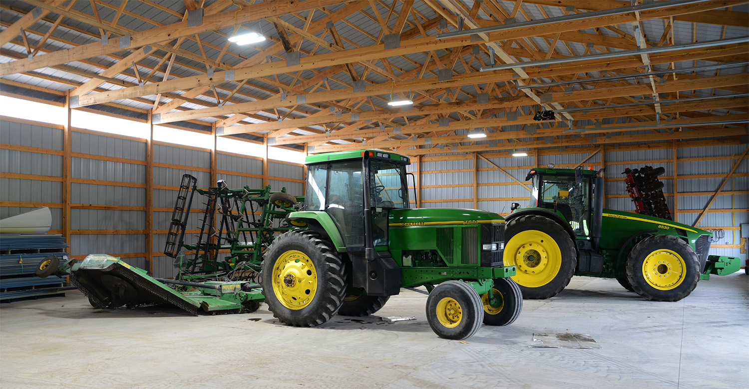 interior showing the framing of of a post frame ag building with two tractors inside