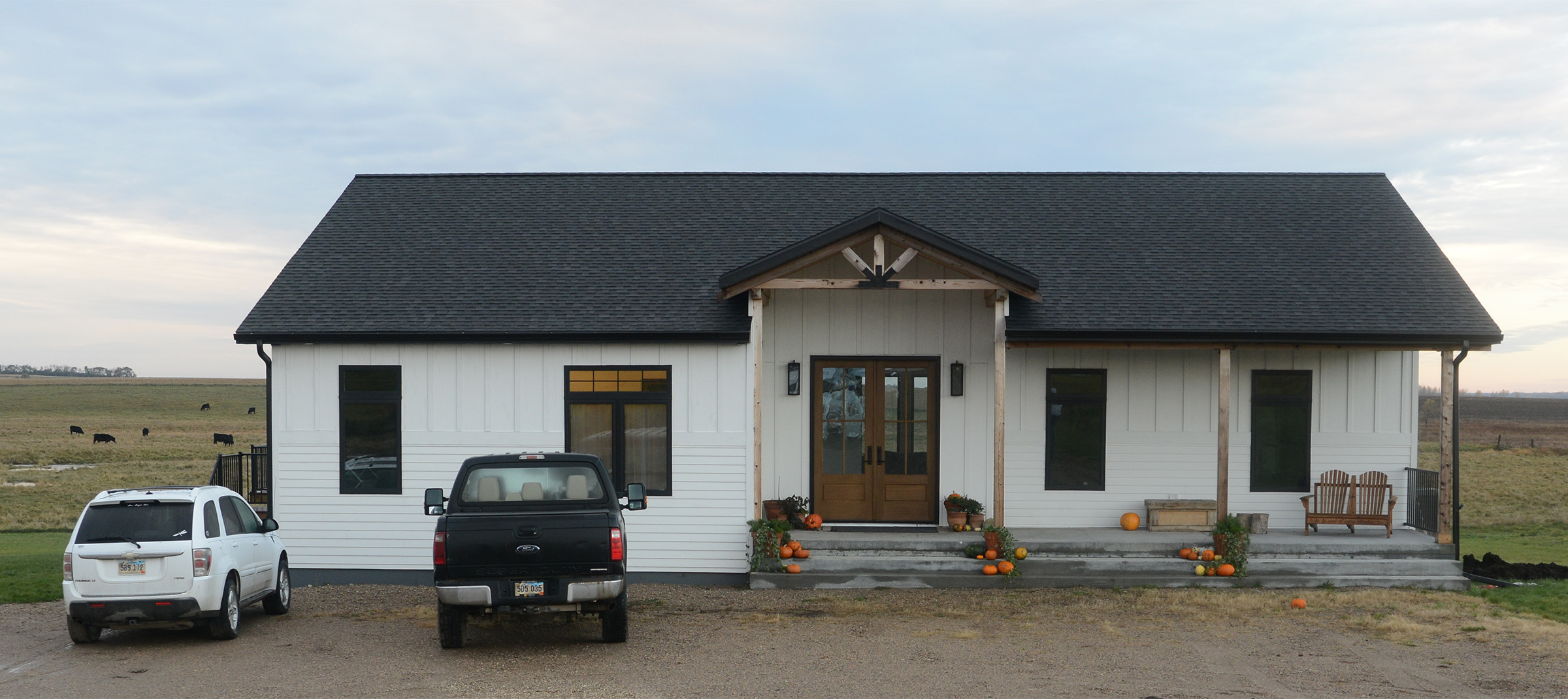 white pole barn home with a black roof